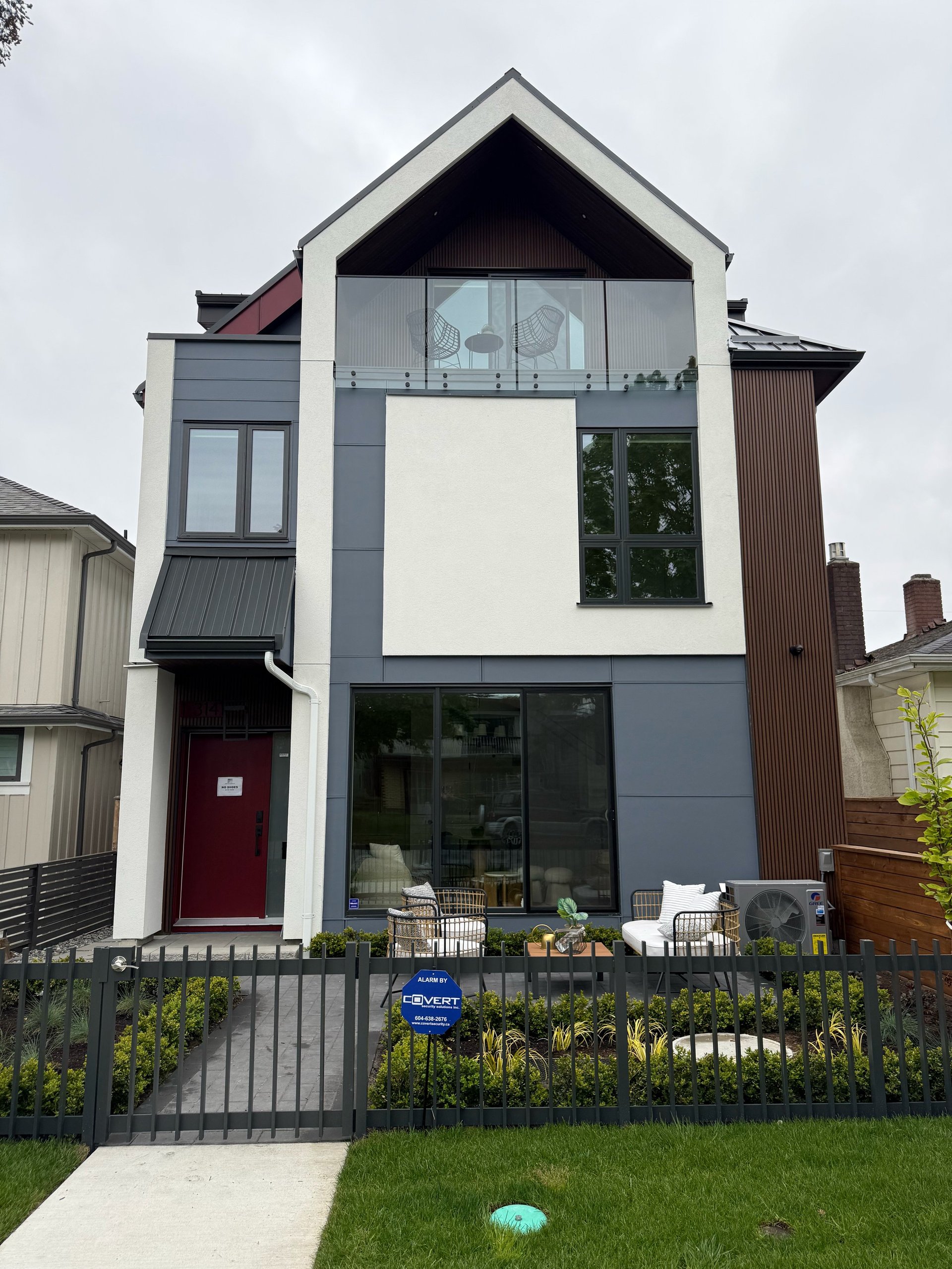 Modern multi-story house with white and dark gray exterior, large windows, red door